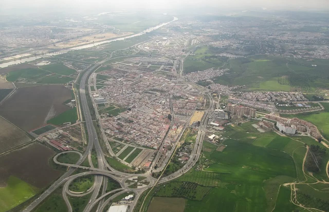 Vista aérea de Camas: el casco urbano encajado entre autovías y enlaces, con campos verdes a la derecha y el río al fondo